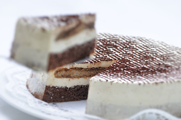 Tiramisu tart with cocoa powder on metal spoon, birthday cake on white plate, patisserie, photography for shop
