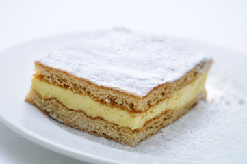 vanilla cream cake with sugar powder on white plate, sweet dessert or breakfast, patisserie, photography for shop