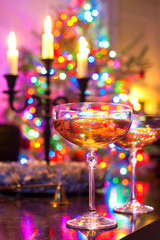 Two champagne glasses on illuminated christmas tree defocused ba