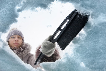 woman cleaning window of car from the snow with a brush