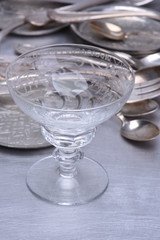 Silver table setting with fork, knife, spoon and glass on gray metal background