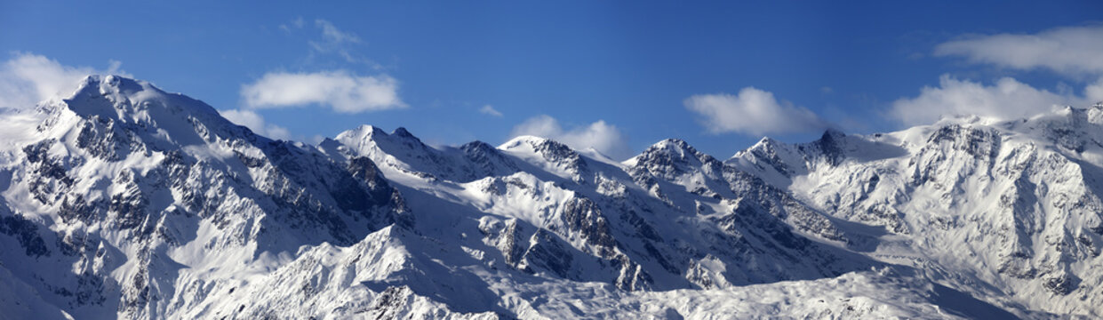 Panoramic view on snowy mountains in sunny day