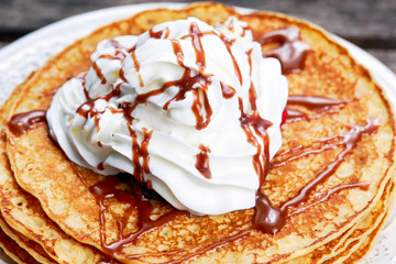 Fresh golden pancakes with cream and chocolate