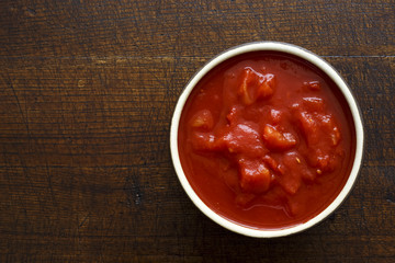 Brown ceramic bowl of chopped tinned tomatoes.