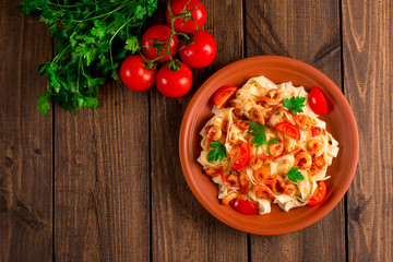Fettuccine pasta with shrimp tomatoes and herbs. wooden background