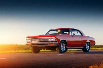 Fotobehang Oldtimers Retro rode auto blijft op asfaltweg bij zonsondergang