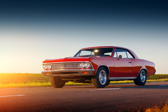 Retro red car stay on asphalt road at sunset