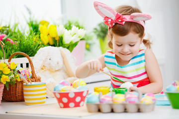  Happy child girl paints eggs for Easter