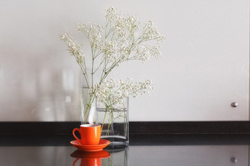 white flowers on a table in glass transparent vases with cup of