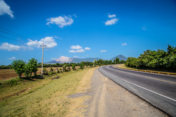 curve road view with volcano at background in blue sky