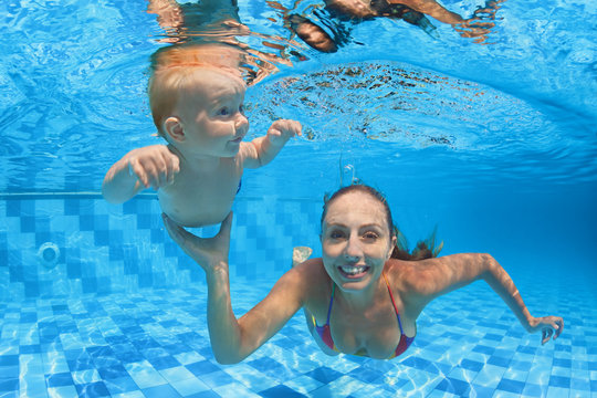 Child swimming lesson - baby with moher learning to dive underwater in pool. Healthy active family lifestyle, physical exercise and water sport activity with parent on summer holiday in fitness center