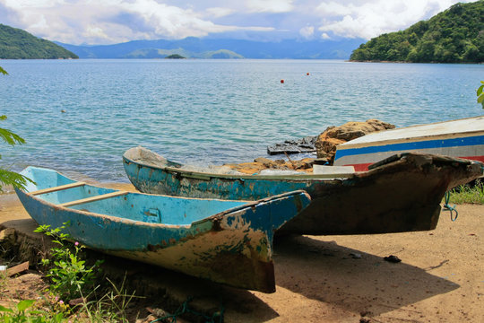 romantic beach scene with green coastline and fisherboats in front, brazil