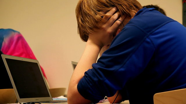 Student thinking in front of his laptop in classroom school