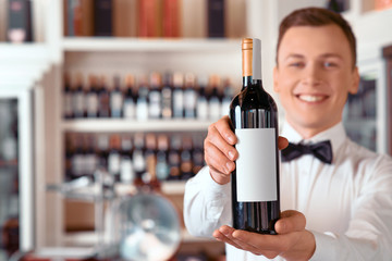 Positive sommelier holding wine bottle 