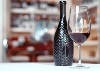 Bottle of wine standing on the table with glass 