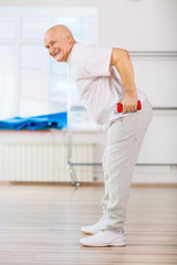 Positive aged man practicing with weights 