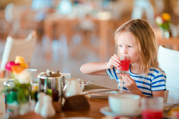 Adorable little girl having breakfast at outdoor cafe