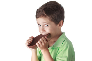 Little boy eating chocolate easter egg on white background