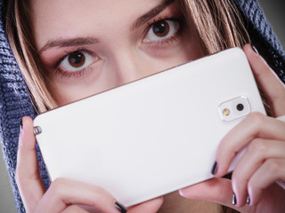 Young woman hiding behind phone.
