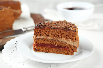 Sliced chocolate cake on wooden table, on light background