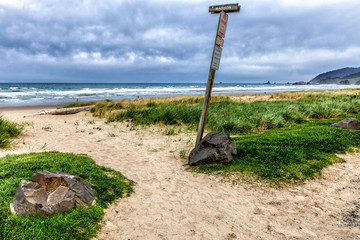Beach with grass covered dunes and miles of sand. Wooden sign wi