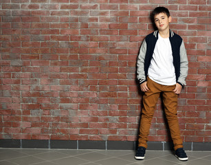 Cute little boy standing near brick wall