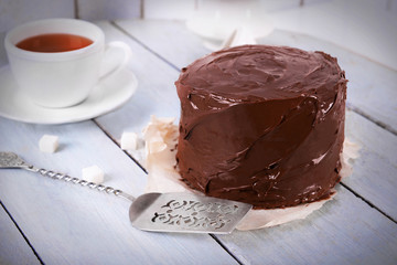 Chocolate cake with cup of tea and blade on a wooden table background