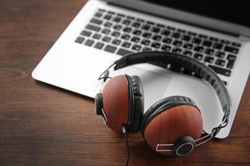 Obraz na płótnie Canvas Headphones and laptop on wooden table closeup