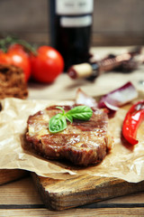 Roasted beef fillet and vegetables on cutting board, on wooden background