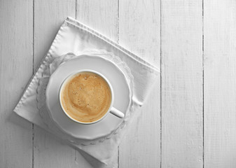 Cup of coffee with foam on wooden background