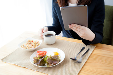タブレットを見るビジネスウーマン　コーヒー　朝食