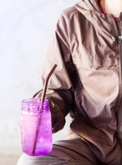 Woman hand holding iced drink in violet glass