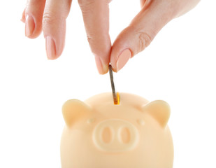 Female hand putting coin into piggy bank isolated on white
