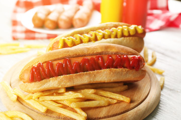Hot dogs and fried potatoes on wooden cutting board closeup