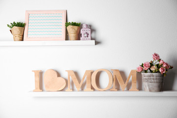 I love mom inscription of wooden letters with heart and flowers on white wall background