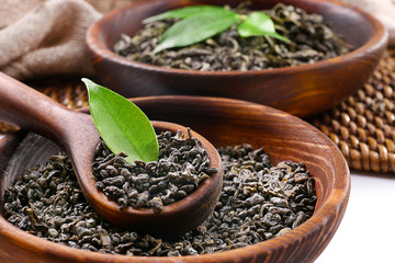 Dry tea with green leaves in wooden utensil, close up
