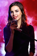 Beautiful singing woman on red background in the smoke, close up