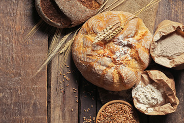 Fresh baked bread, flour and wheat on the wooden background
