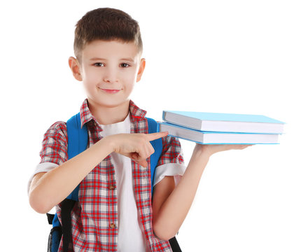 Little Boy With Back Pack Pointing To Books, Isolated On White