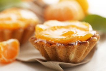 Sweet cakes with tangerines on table, close up