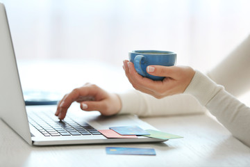 Fototapeta premium E-commerce concept. Woman with credit card, laptop and cup of coffee, close up