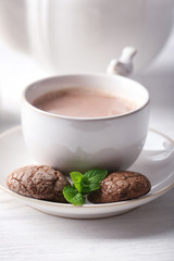 Cup of cocoa with chocolate chip cookies and mint on light background