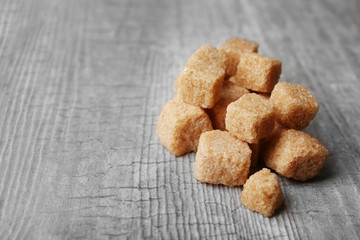 Pile of brown sugar cubes on wooden background