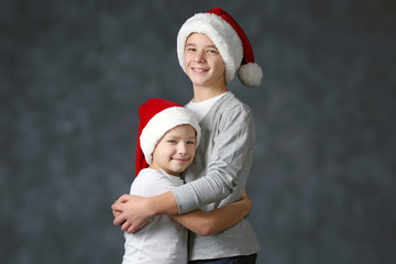 Obraz premium Brothers in Santa hats on grey background
