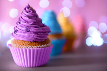Cupcake with purple cream icing on a glitter background, close up