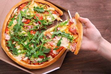 Piece of fresh pizza in hand closeup