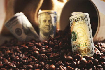 Coffee beans, cup and US dollar banknotes on wooden background