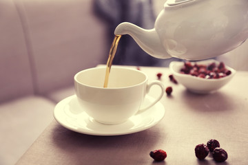 Pouring rose hip tea into cup, home atmosphere