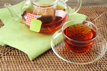 Cup of tea with tea bags and teapot on wooden table background