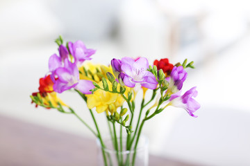 Fototapeta na wymiar Beautiful bouquet of colorful freesias flowers on wooden table at living room